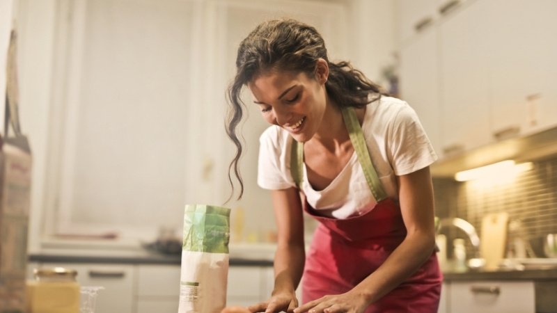 Mulher fazendo renda extra cozinhando em casa feliz